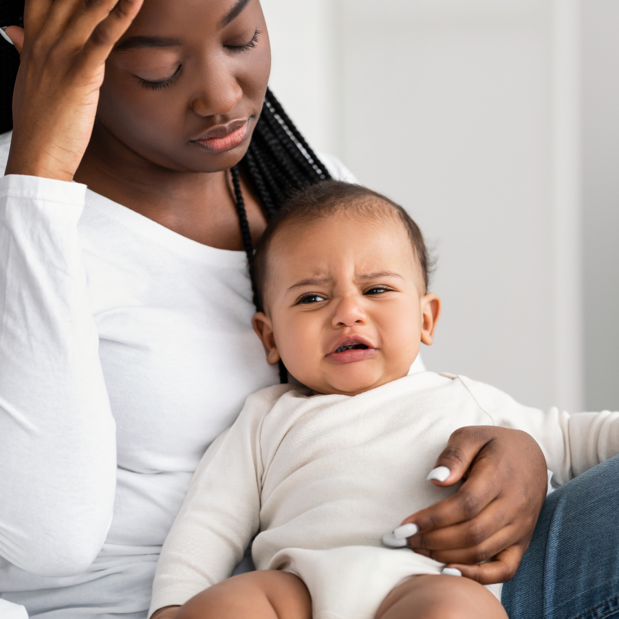 A stressed woman holding her baby, reflecting postpartum challenges and the emotional strain of new motherhood.